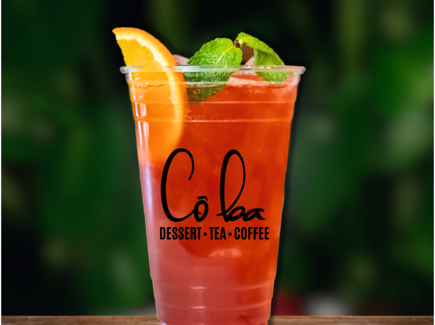 A refreshing Hibiscus Breeze drink garnished with an orange slice and fresh mint leaves.