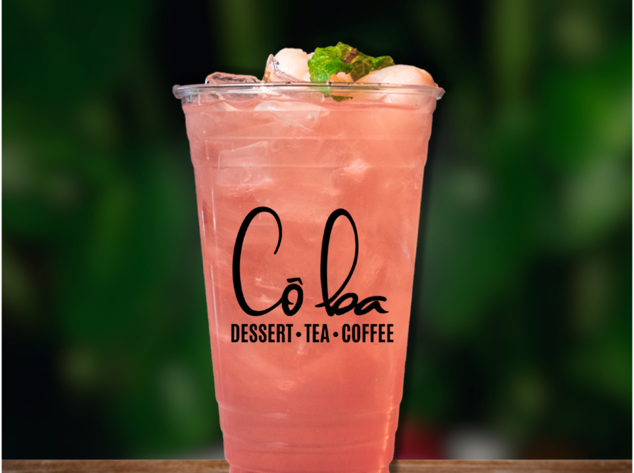 A refreshing Lychee Rose drink with a straw sits on a wooden table, inviting and colorful.